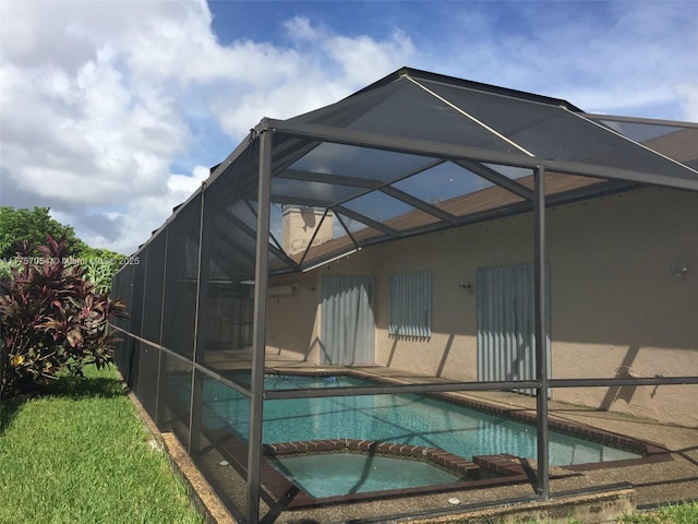 view of swimming pool with glass enclosure, a pool with connected hot tub, and a patio area