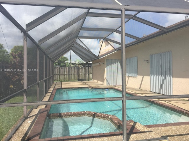 view of swimming pool featuring a patio area, a pool with connected hot tub, and glass enclosure