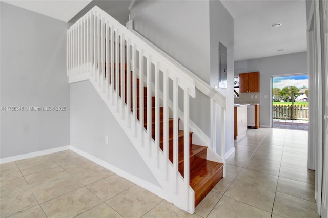 staircase with tile patterned flooring, electric panel, and baseboards