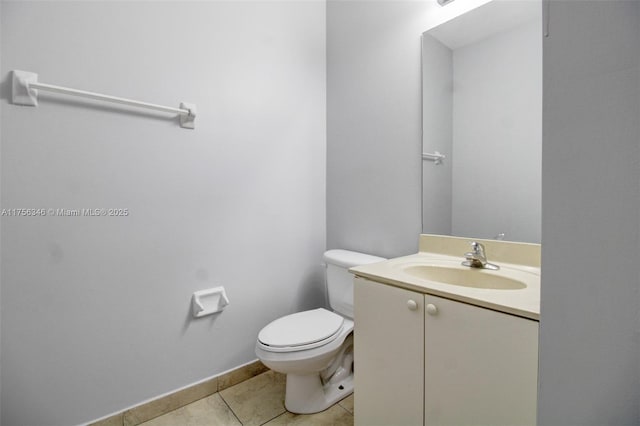 half bath featuring toilet, vanity, baseboards, and tile patterned floors