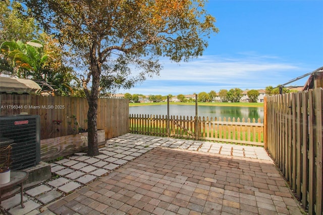 view of patio with a water view, fence, and central AC unit