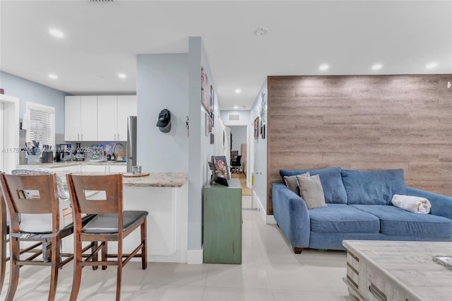 kitchen with recessed lighting, a sink, white cabinetry, and a kitchen breakfast bar