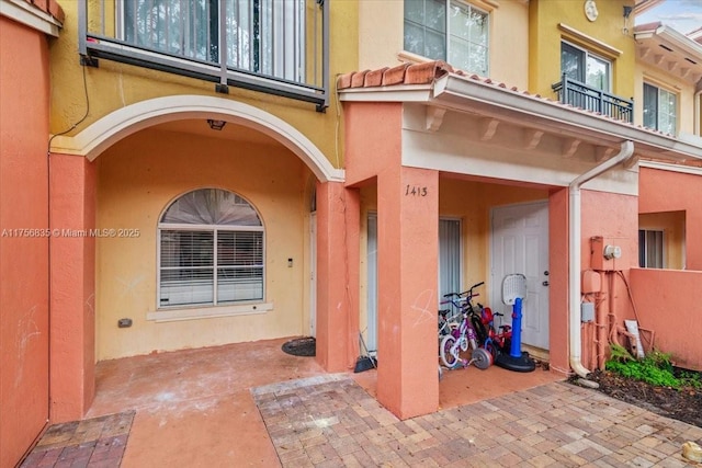 doorway to property featuring a tile roof and stucco siding