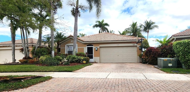 view of front of property featuring stucco siding, a garage, a tiled roof, and decorative driveway