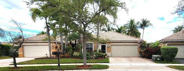 ranch-style house featuring driveway, a front lawn, a tile roof, and stucco siding