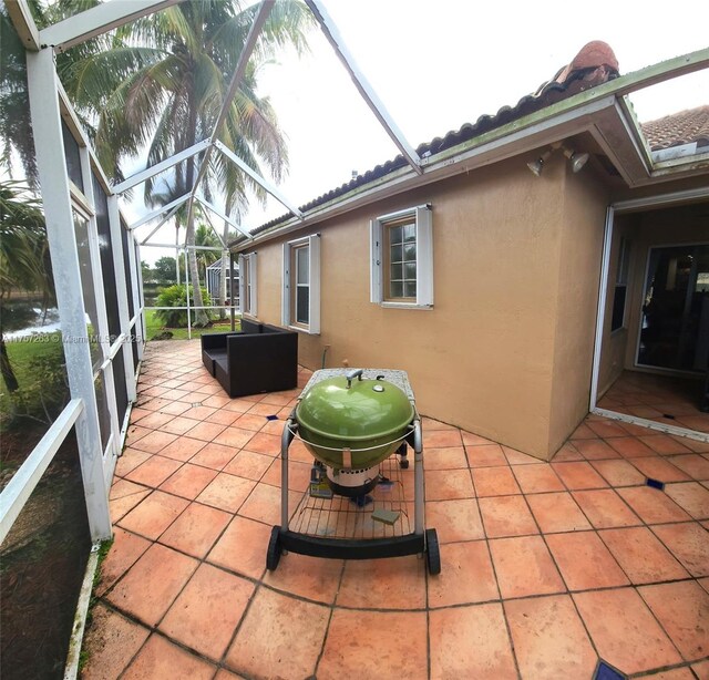 view of patio with glass enclosure and area for grilling