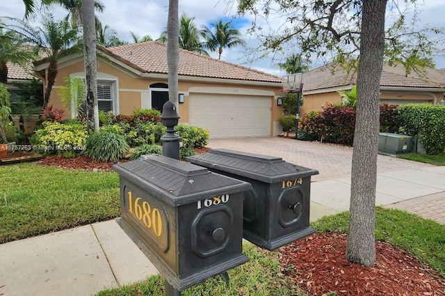 view of front of property featuring driveway, an attached garage, a tiled roof, and stucco siding