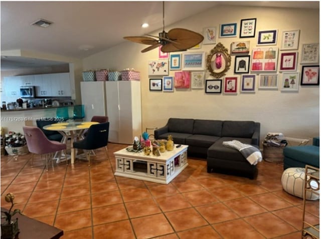 tiled living room with lofted ceiling, visible vents, and a ceiling fan