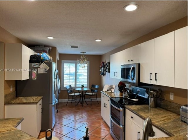 kitchen with white cabinets, light tile patterned flooring, and stainless steel appliances