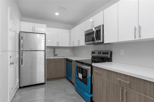 kitchen with light countertops, visible vents, appliances with stainless steel finishes, white cabinetry, and a sink