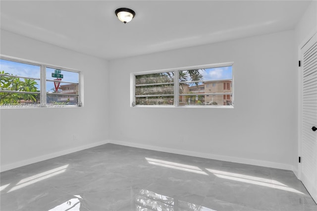 unfurnished bedroom featuring concrete flooring, a closet, and baseboards