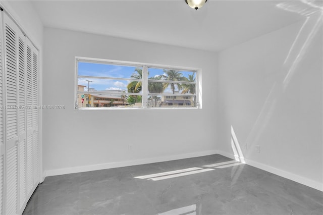 unfurnished bedroom with concrete floors, baseboards, and a closet