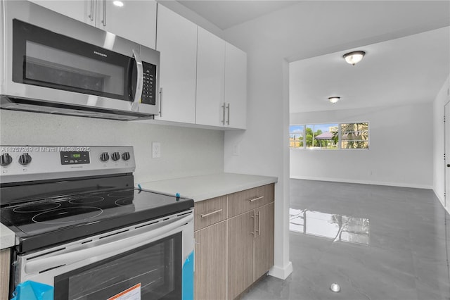 kitchen with white cabinetry, baseboards, light countertops, appliances with stainless steel finishes, and modern cabinets