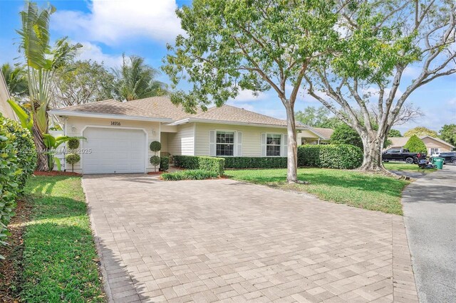 ranch-style house with a front lawn, decorative driveway, an attached garage, and fence