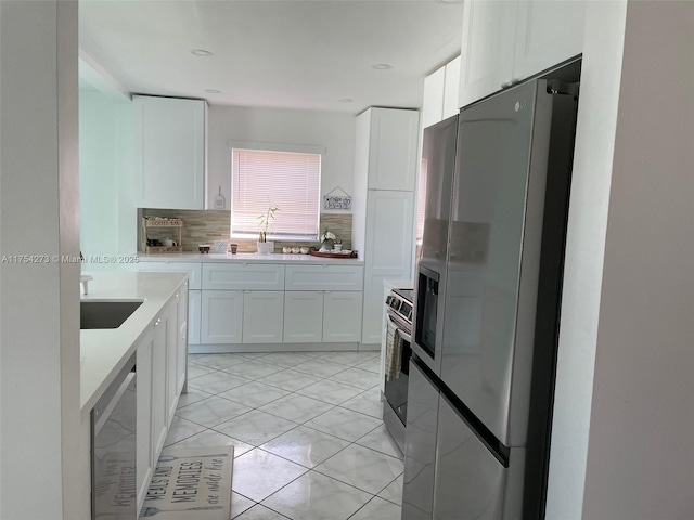 kitchen with white cabinets, decorative backsplash, stainless steel appliances, light countertops, and a sink