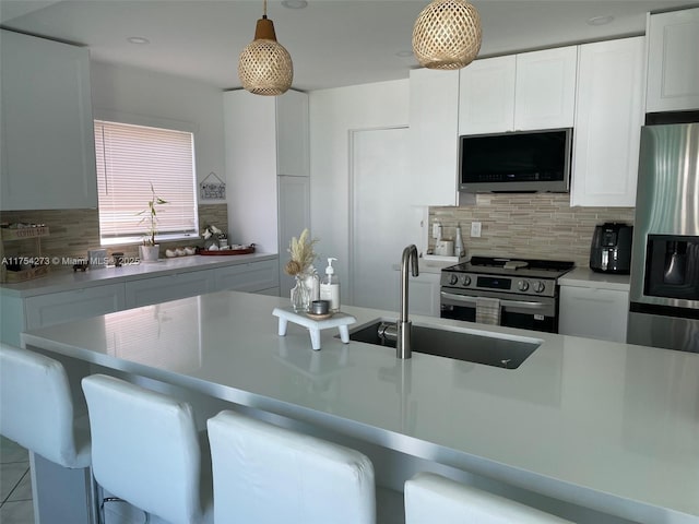 kitchen with a sink, appliances with stainless steel finishes, a kitchen bar, and backsplash