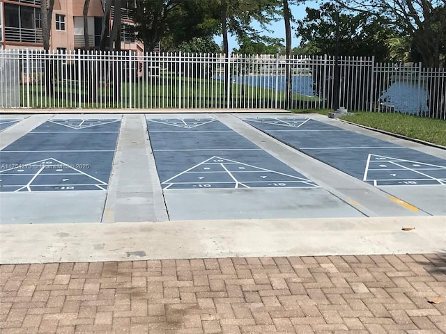 view of community with shuffleboard and fence