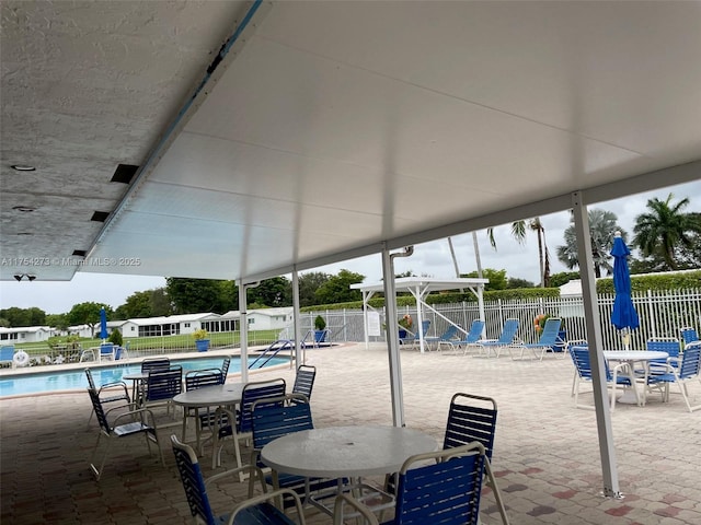 view of patio featuring outdoor dining area, fence, and a community pool