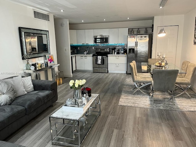 living room featuring dark wood-style flooring, visible vents, and recessed lighting