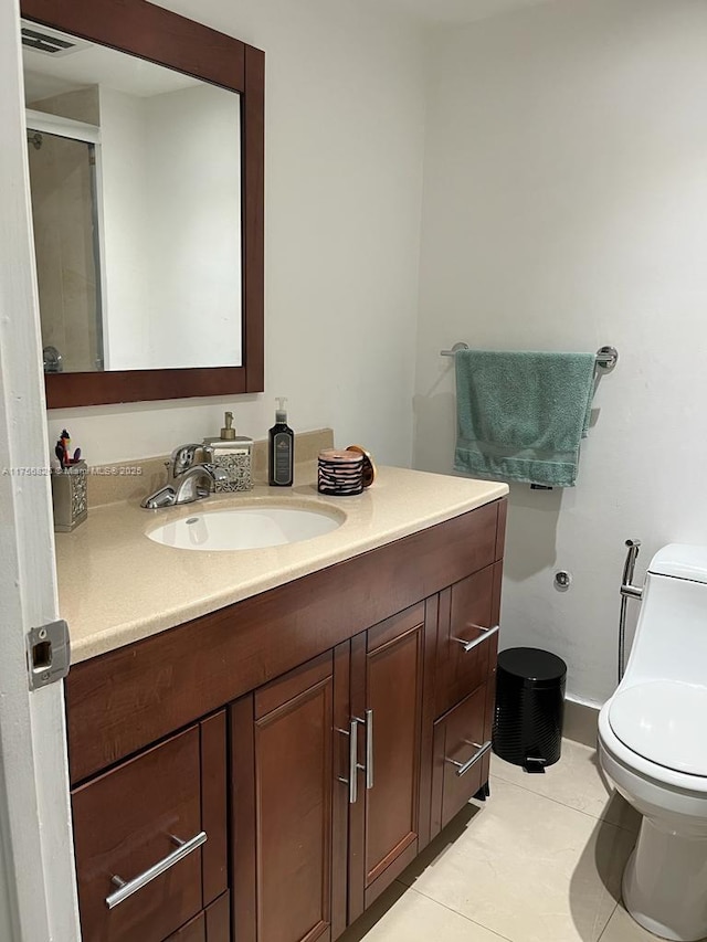 bathroom featuring a shower with door, visible vents, toilet, vanity, and tile patterned floors