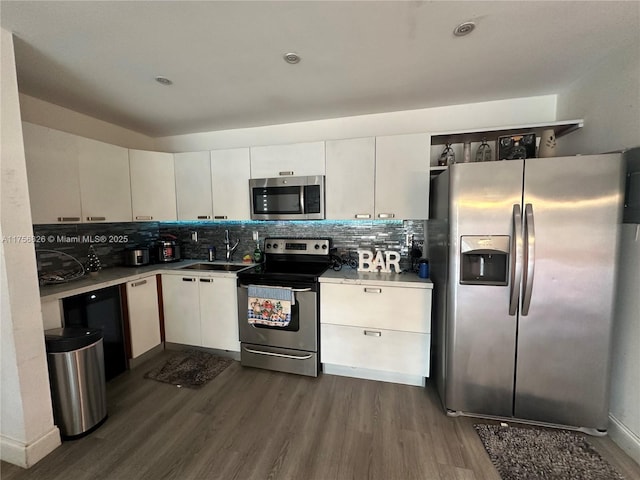 kitchen featuring dark wood-style floors, tasteful backsplash, appliances with stainless steel finishes, and a sink