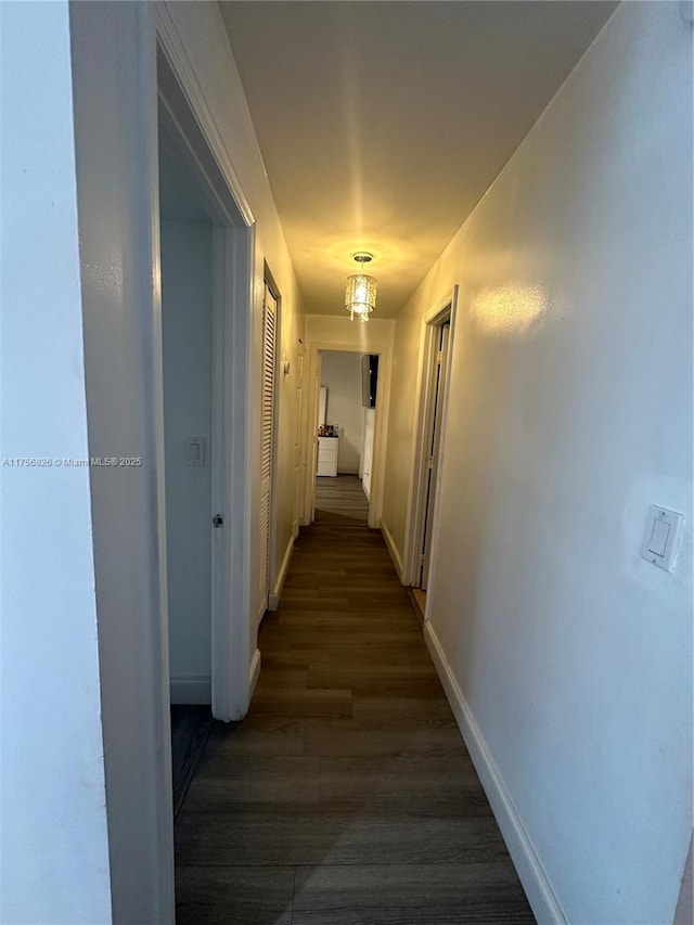 corridor with dark wood finished floors and baseboards