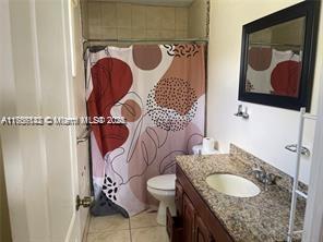 bathroom with tile patterned flooring, curtained shower, vanity, and toilet