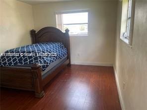 bedroom with dark wood-style floors and baseboards