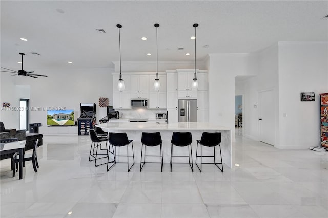 kitchen featuring light countertops, visible vents, appliances with stainless steel finishes, white cabinetry, and a kitchen breakfast bar