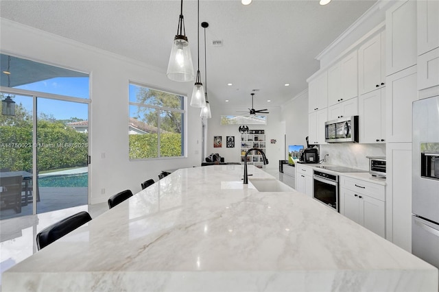 kitchen with stainless steel appliances, a sink, a large island, and ornamental molding