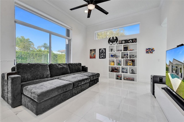 living room with crown molding, a towering ceiling, baseboards, and ceiling fan