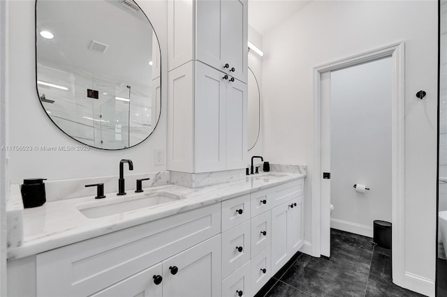 bathroom featuring double vanity, a shower stall, toilet, and a sink