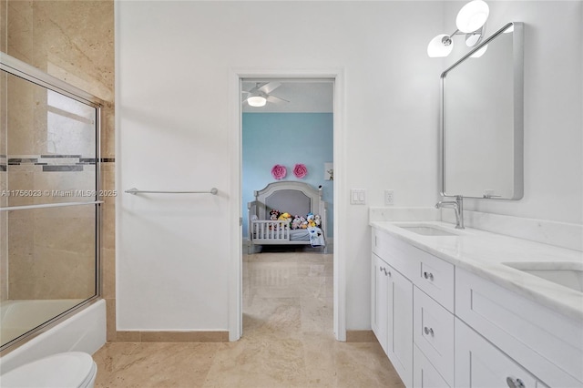 bathroom featuring double vanity, bath / shower combo with glass door, toilet, and a sink