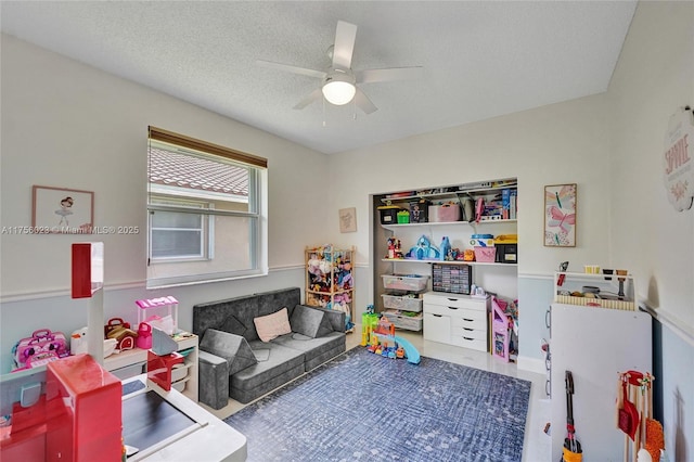 game room with a ceiling fan and a textured ceiling