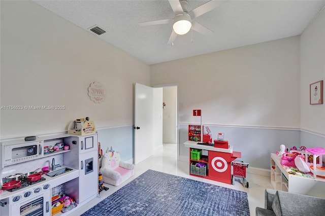 rec room with ceiling fan, visible vents, a textured ceiling, and tile patterned floors