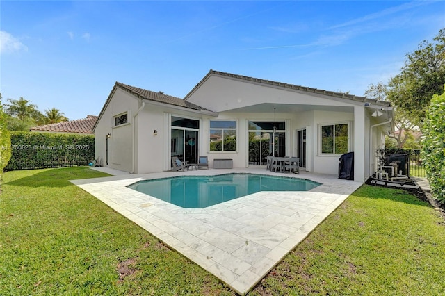 rear view of property with a patio area, a fenced in pool, a lawn, and stucco siding