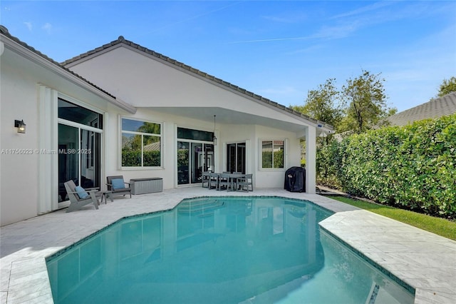 back of house featuring an outdoor pool, a patio, and stucco siding