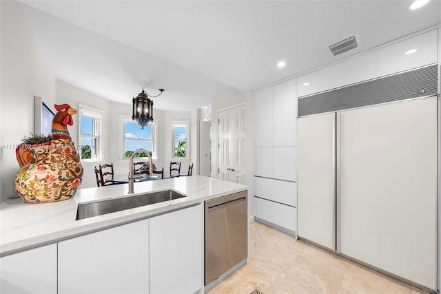 kitchen featuring visible vents, dishwasher, built in refrigerator, white cabinetry, and a sink