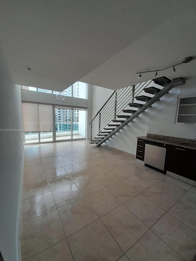 unfurnished room featuring stairway, a sink, and light tile patterned flooring