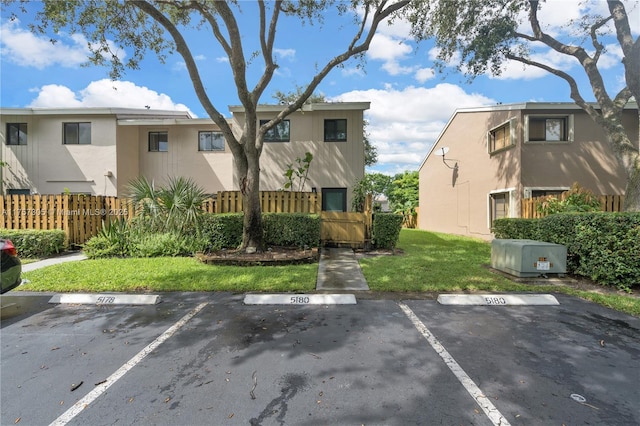 exterior space with uncovered parking, a yard, fence, and stucco siding