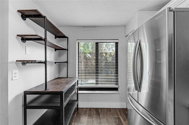 interior space featuring a textured ceiling, baseboards, dark wood-style flooring, and freestanding refrigerator