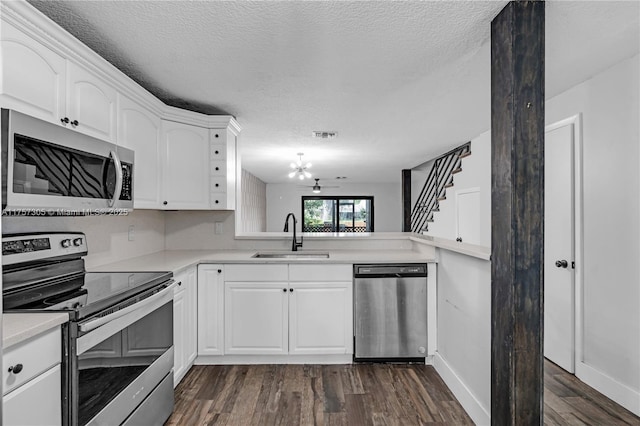 kitchen featuring a textured ceiling, stainless steel appliances, a sink, light countertops, and dark wood finished floors