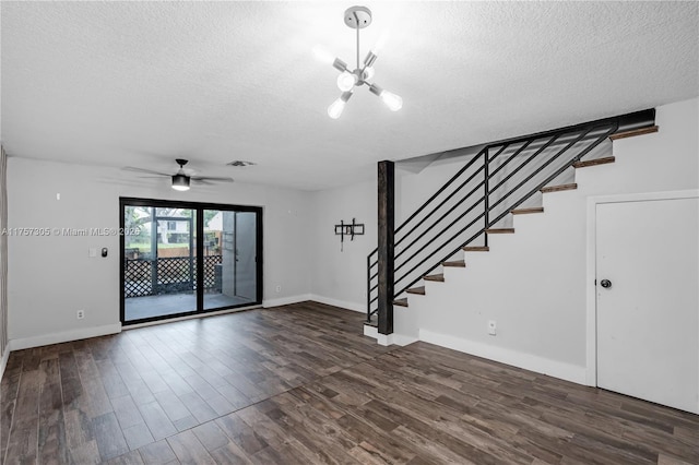 spare room featuring dark wood finished floors, a textured ceiling, and stairs