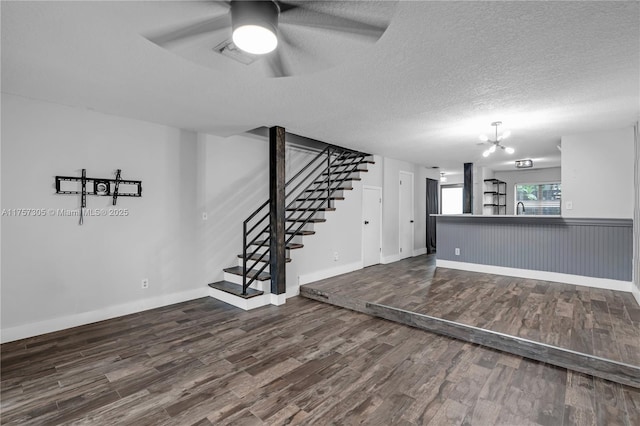 unfurnished room featuring dark wood-style flooring, baseboards, stairway, and a textured ceiling