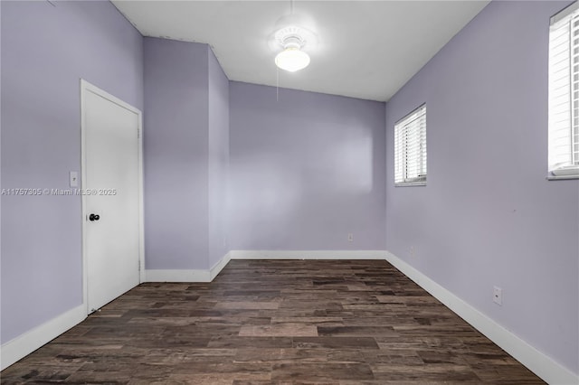 empty room with dark wood-style flooring and baseboards