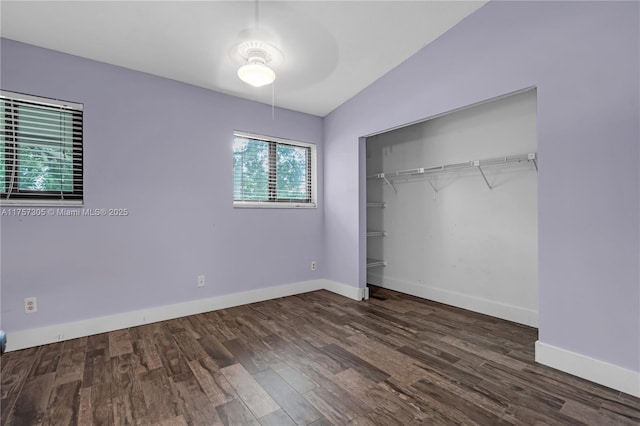 unfurnished bedroom with baseboards, ceiling fan, wood finished floors, vaulted ceiling, and a closet