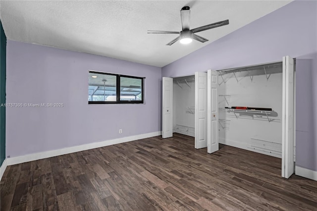 unfurnished bedroom featuring lofted ceiling, a textured ceiling, wood finished floors, a ceiling fan, and multiple closets