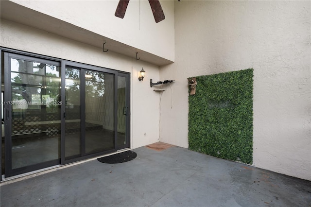 view of exterior entry featuring ceiling fan, a patio, and stucco siding