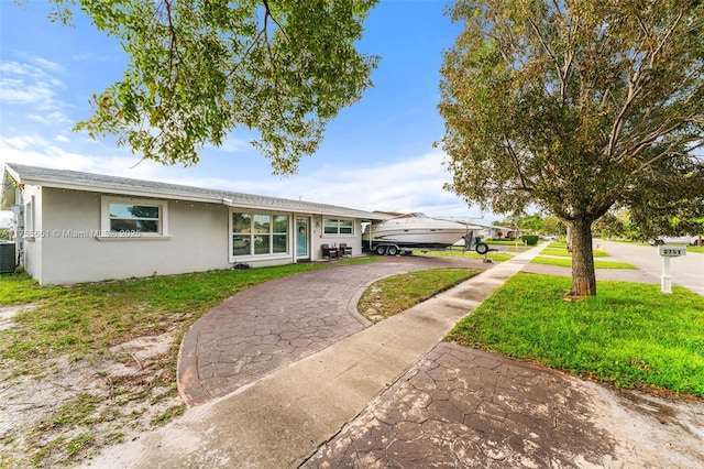 single story home with central AC unit, aphalt driveway, a front yard, and stucco siding