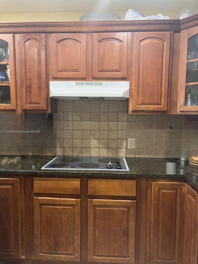 kitchen featuring black electric stovetop, decorative backsplash, glass insert cabinets, and under cabinet range hood